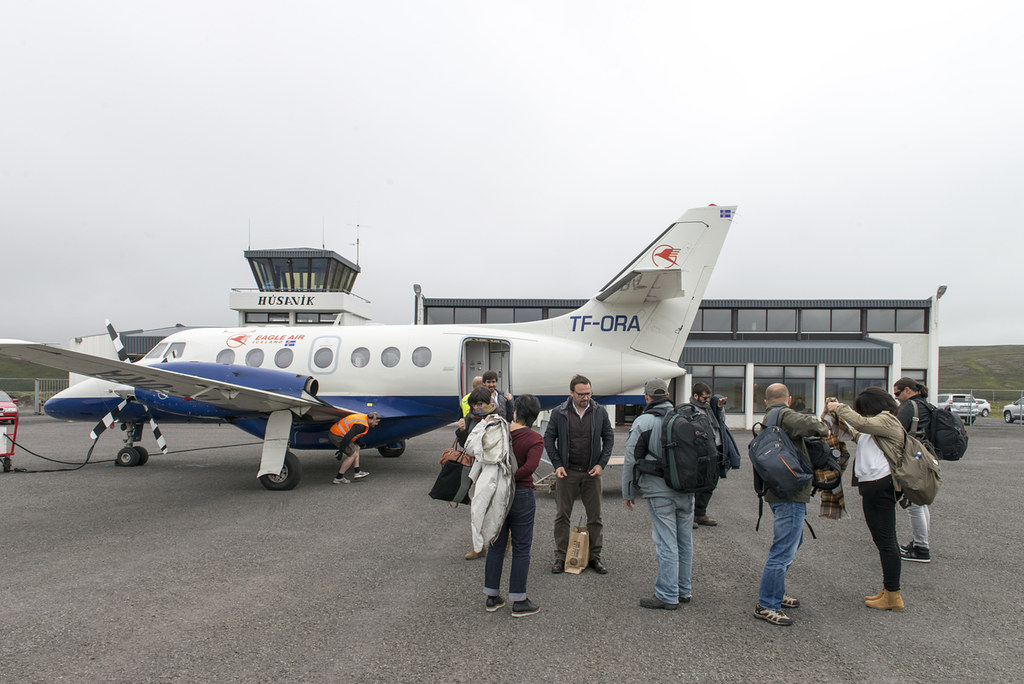 Grupo de jornalistas a desembarcar de avião Eagle Air na pista do aeroporto de Húsavík, Islândia