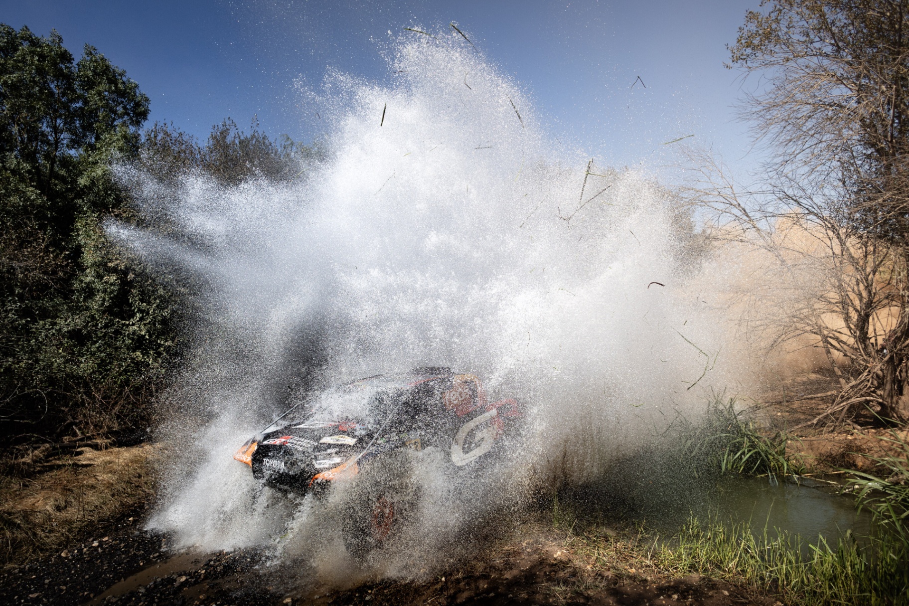 Toyota GR DKR Hilux a cortar leito de água com explosão de salpicos