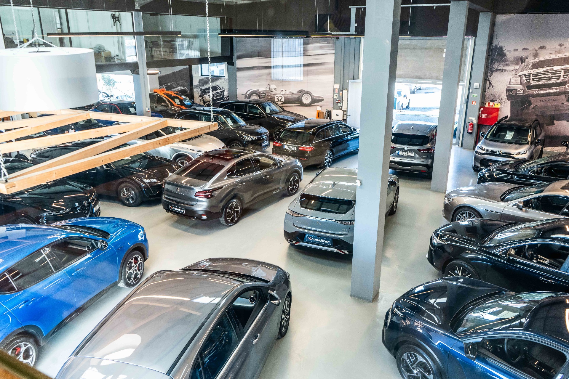 Vista interior do showroom Consilcar em Sintra com dezenas de viaturas usadas e seminovas alinhadas sobre pavimento claro, sob iluminação industrial