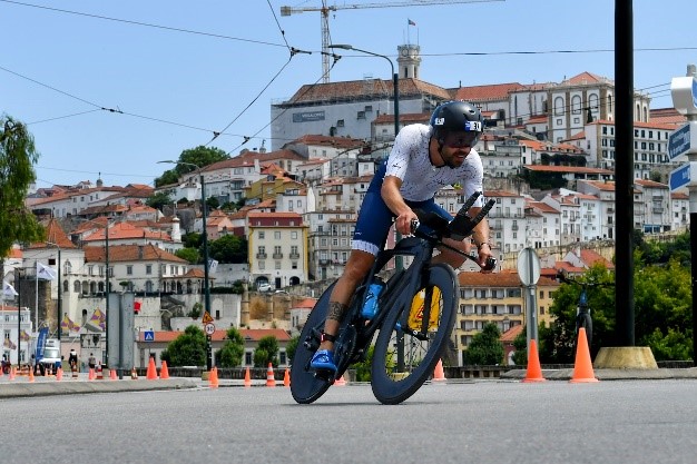 Triatleta em bicicleta de contrarrelógio com a Universidade de Coimbra ao fundo