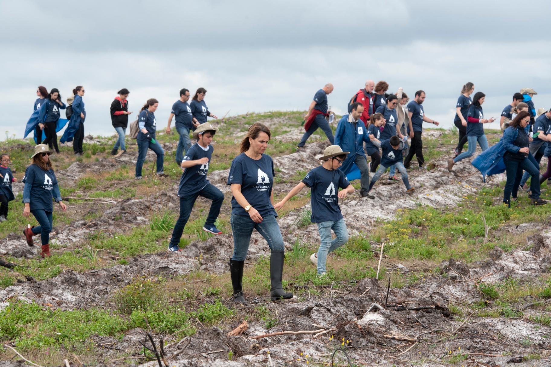 Voluntários de t-shirt Leaf4Trees a caminhar pelo terreno de plantação
