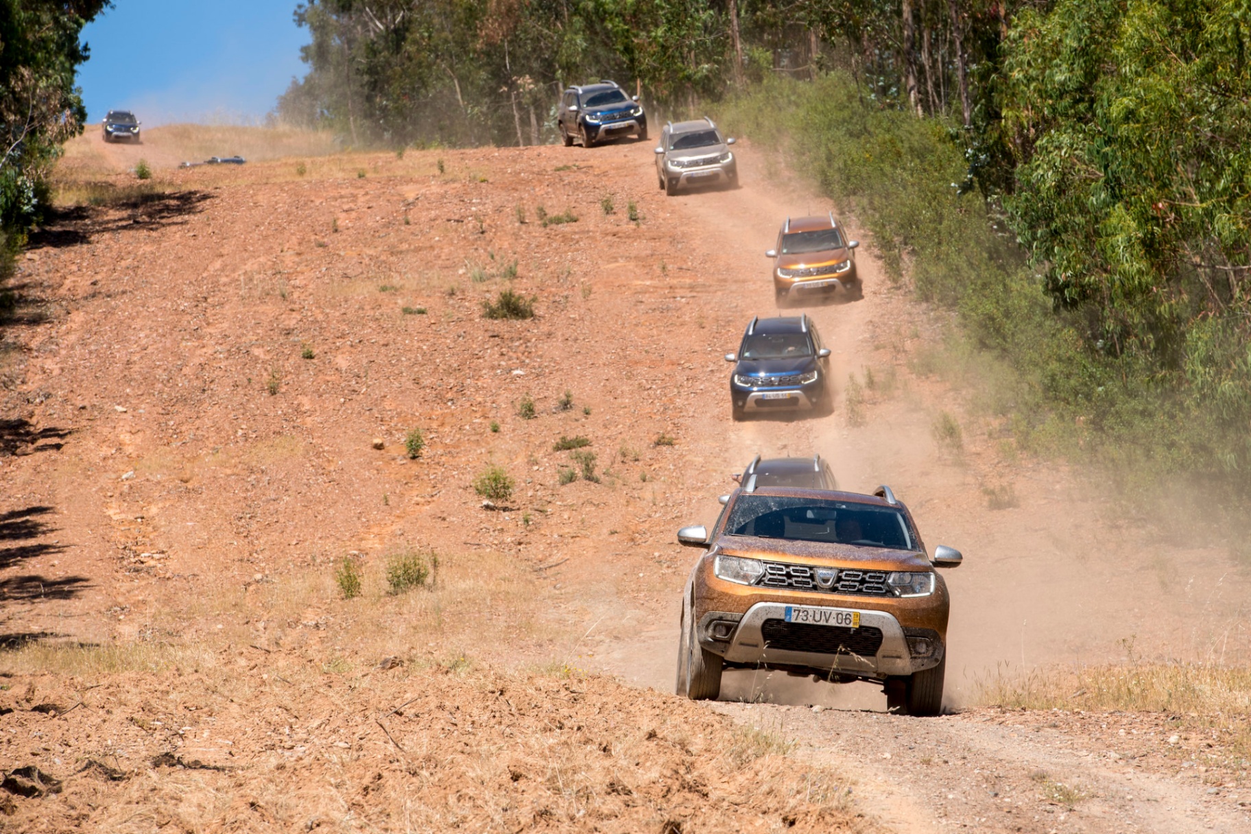 Comboio de Dacia Duster em descida poeirenta em trilho off-road alentejano