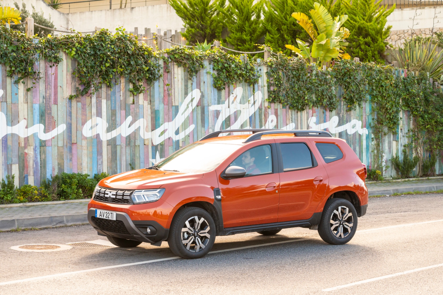 Dacia Duster laranja estacionado junto a mural colorido na Ericeira