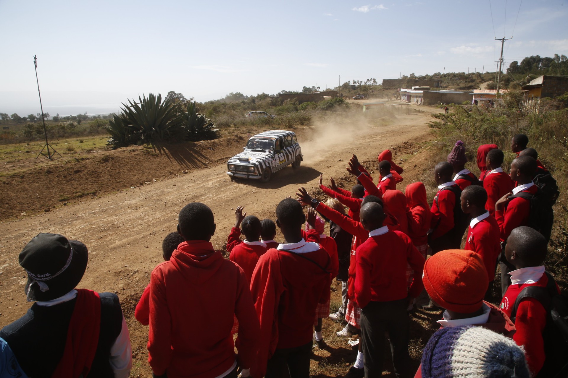 Crianças quenianas de vermelho saúdam a Renault 4L zebra em prova
