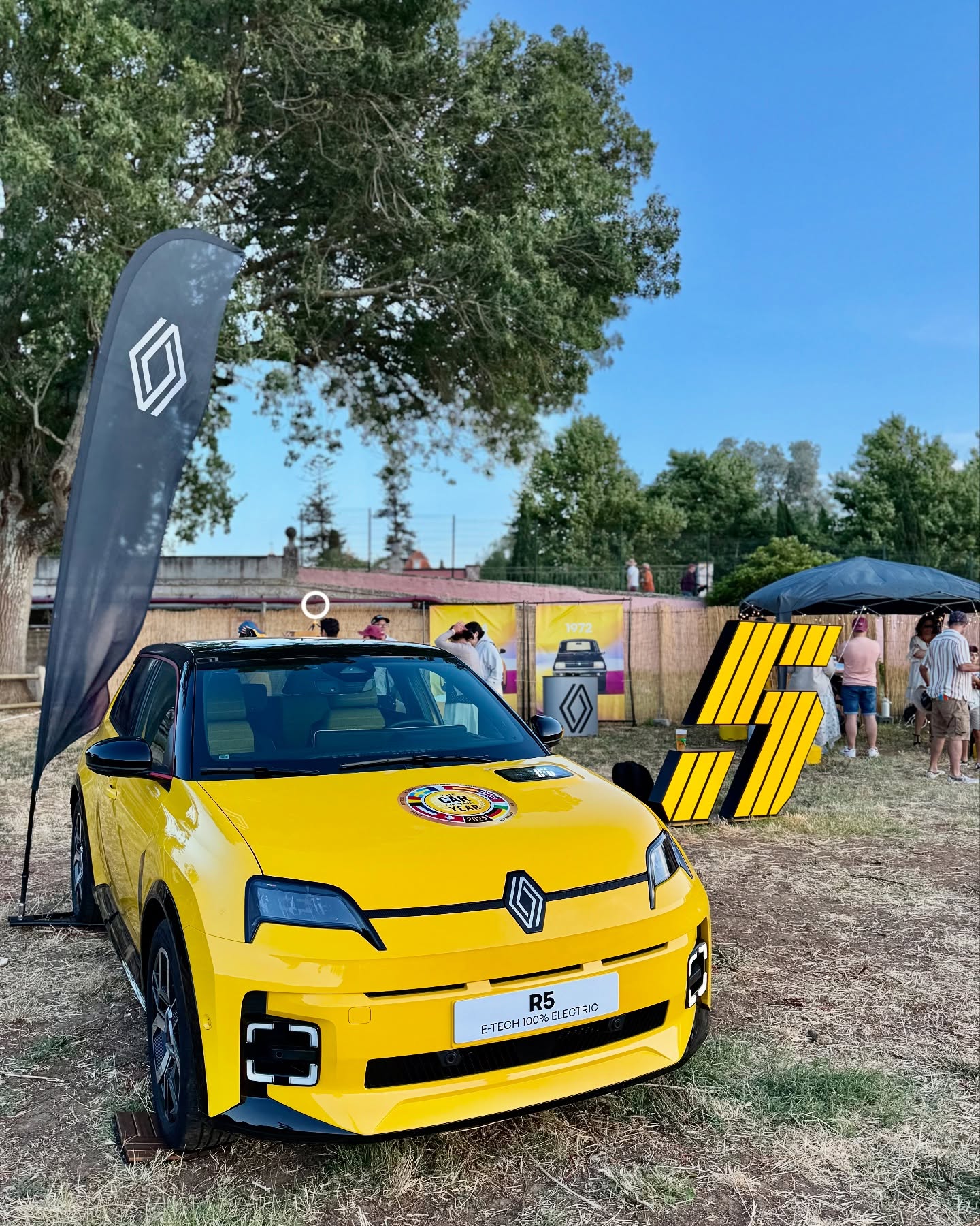 Renault 5 E-Tech amarelo em exposição no Santander Fest, com bandeira Renault e letras gigantes «5»
