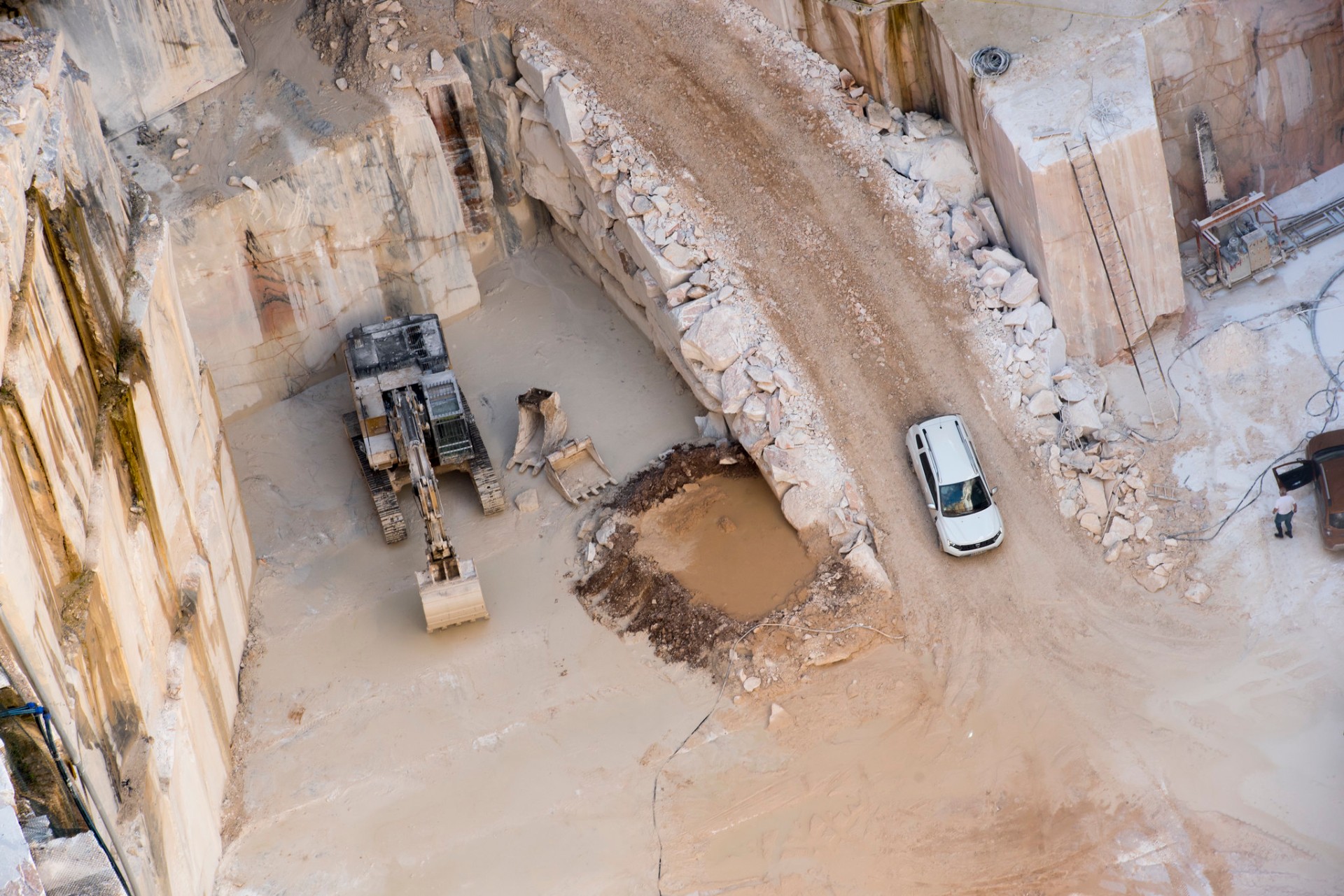 Vista aérea da pedreira com máquina escavadora e Dacia em operação