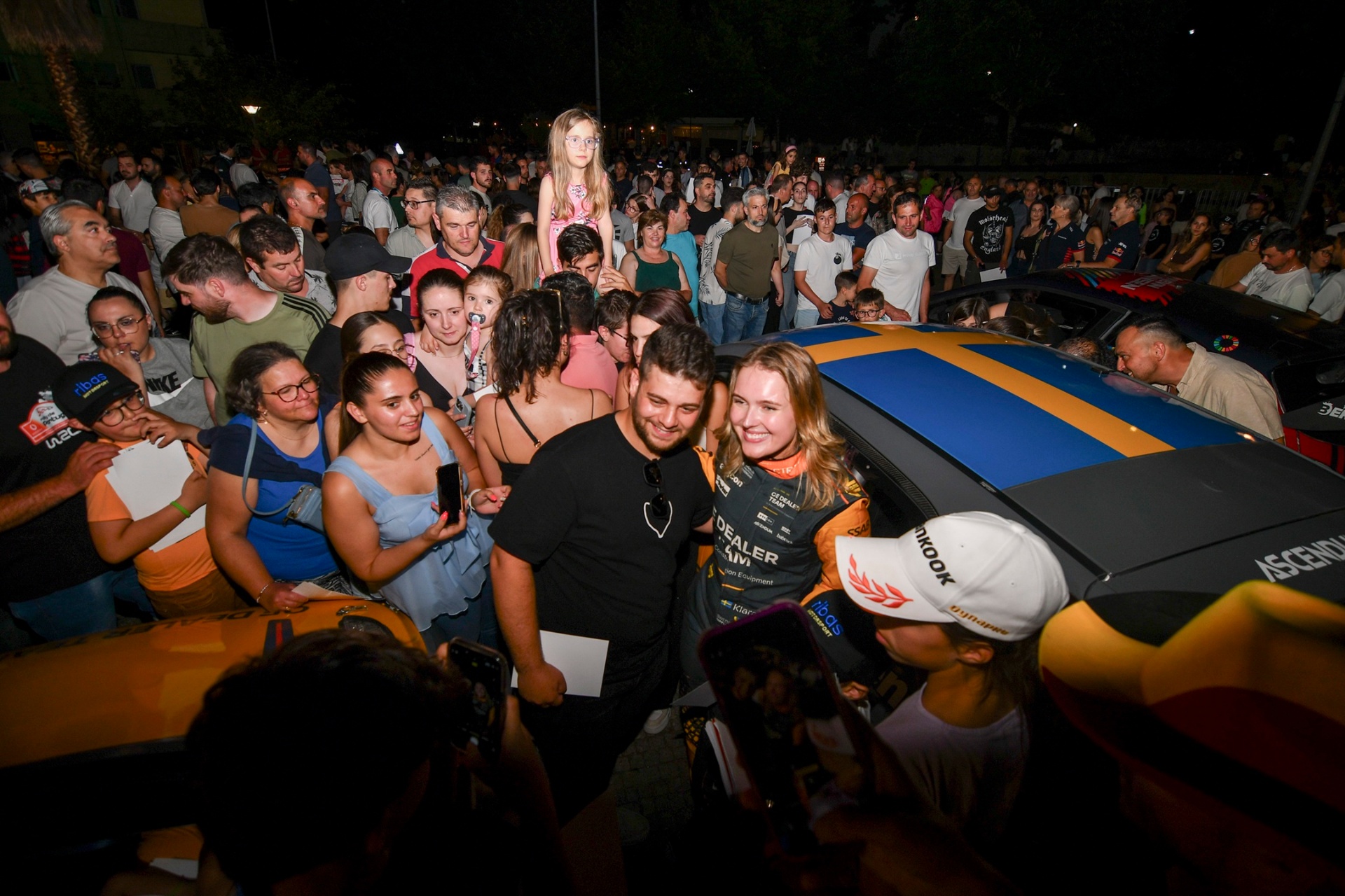 Klara Andersson a posar para fotografia com fãs junto ao carro no parque fechado noturno