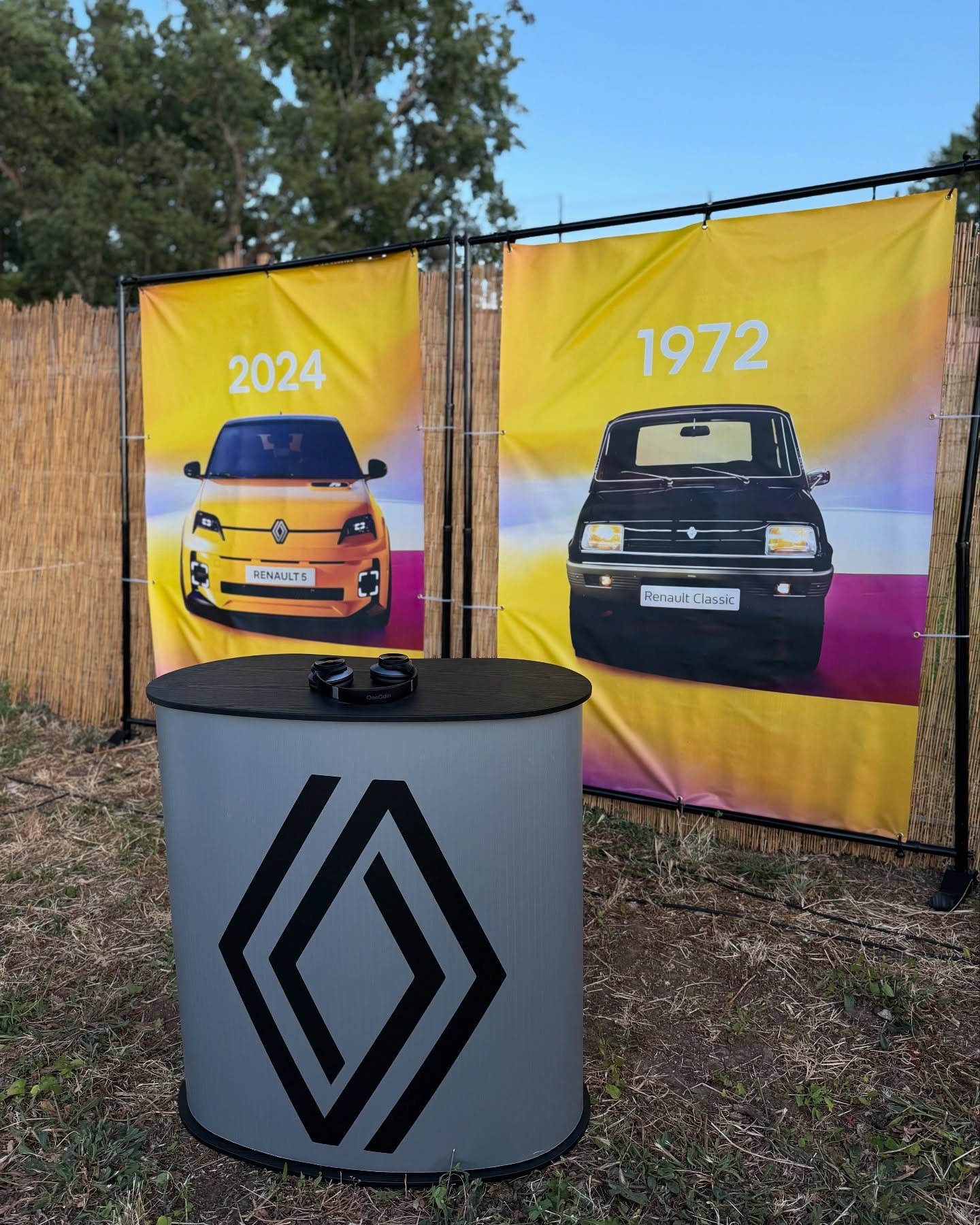 Banners «2024» e «1972» com o novo Renault 5 e o Renault 5 clássico, junto a balcão com auscultadores