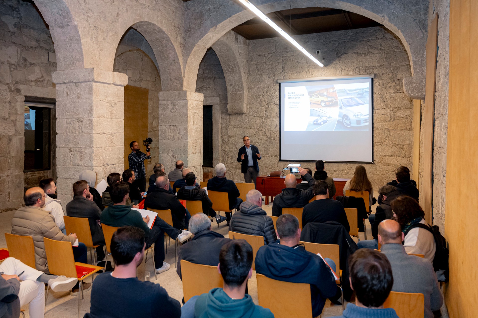 Conferência de imprensa em sala de arcos em pedra com apresentação sobre a história do Clio