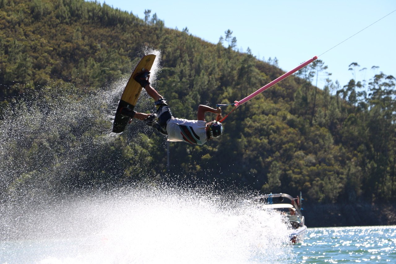 Atleta de wakeboard em salto sobre albufeira do interior