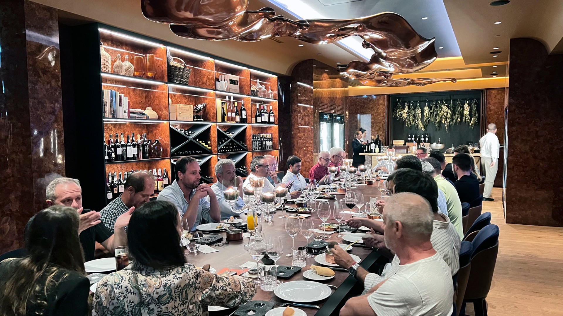 Jantar com jornalistas em sala de garrafeira com escultura de cobre suspensa