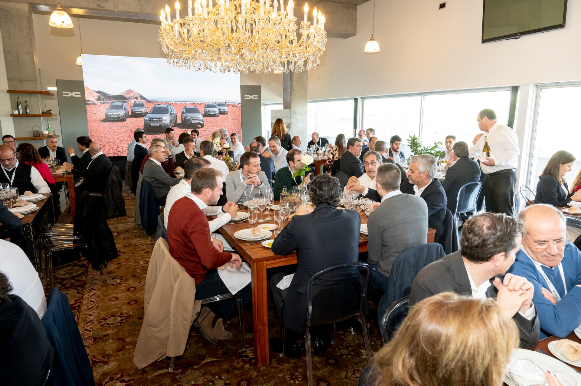 Almoço da Convenção Rede Dacia sob lustre de cristal com gama Dacia projetada no fundo