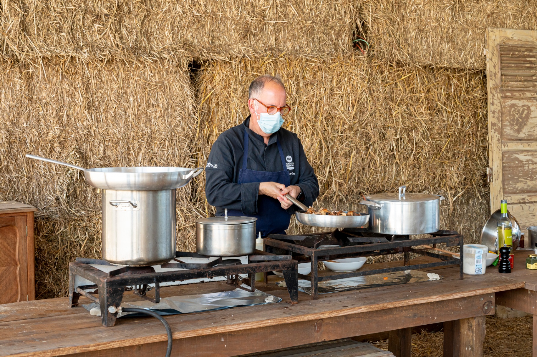 Chef a cozinhar num fogão a gás, com fardos de palha como cenário