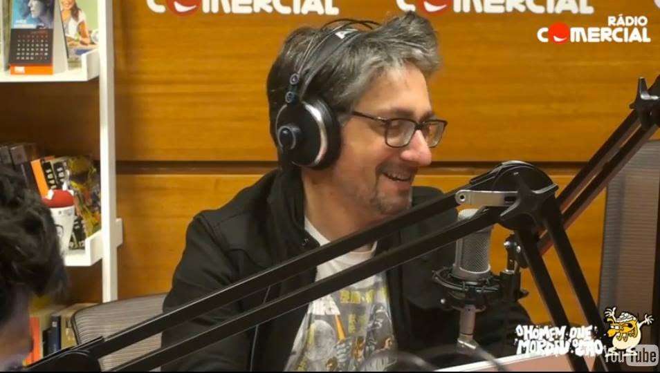 Nuno Markl com auscultadores em estúdio das Manhãs da Comercial, sorrindo junto ao microfone