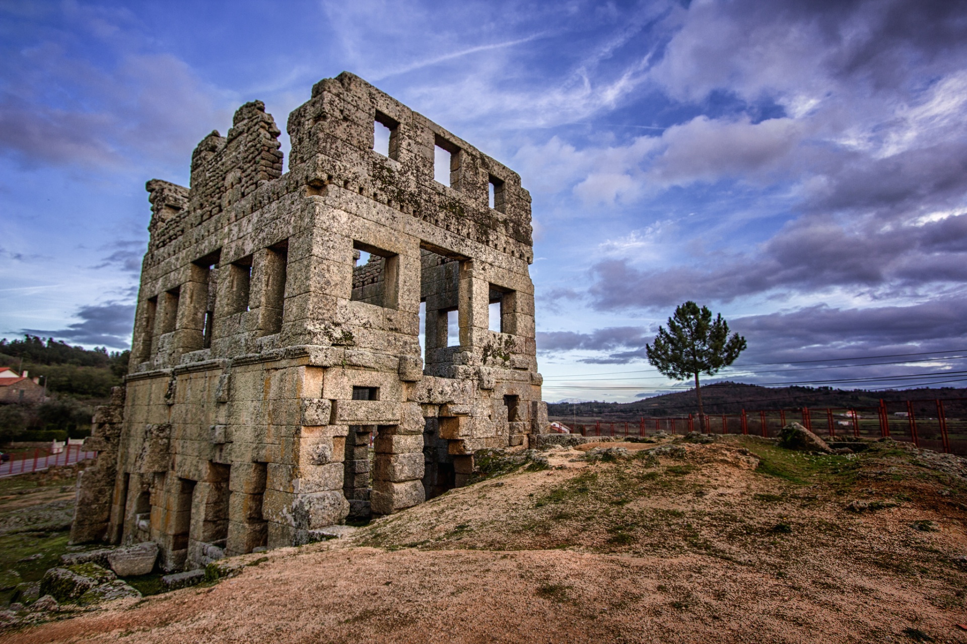 Torre romana de Centum Cellas em Belmonte sob céu de nuvens dramáticas