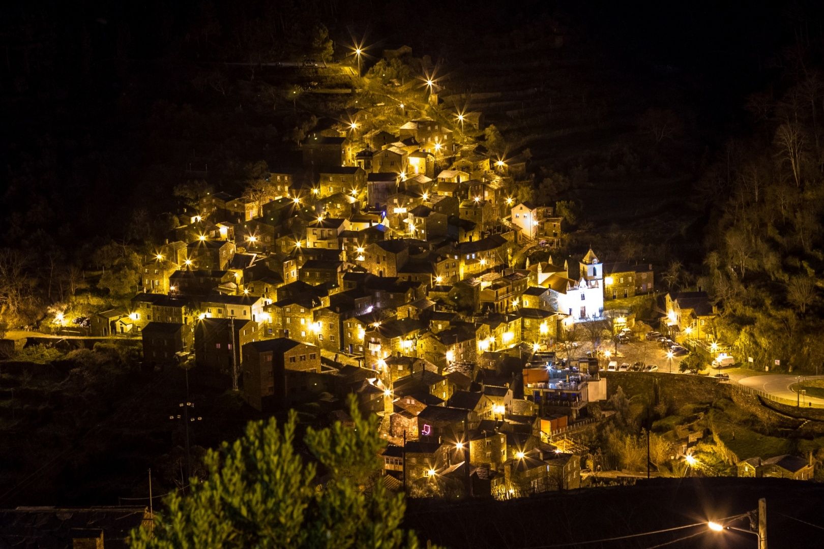 Aldeia do Piódão iluminada à noite na encosta da serra