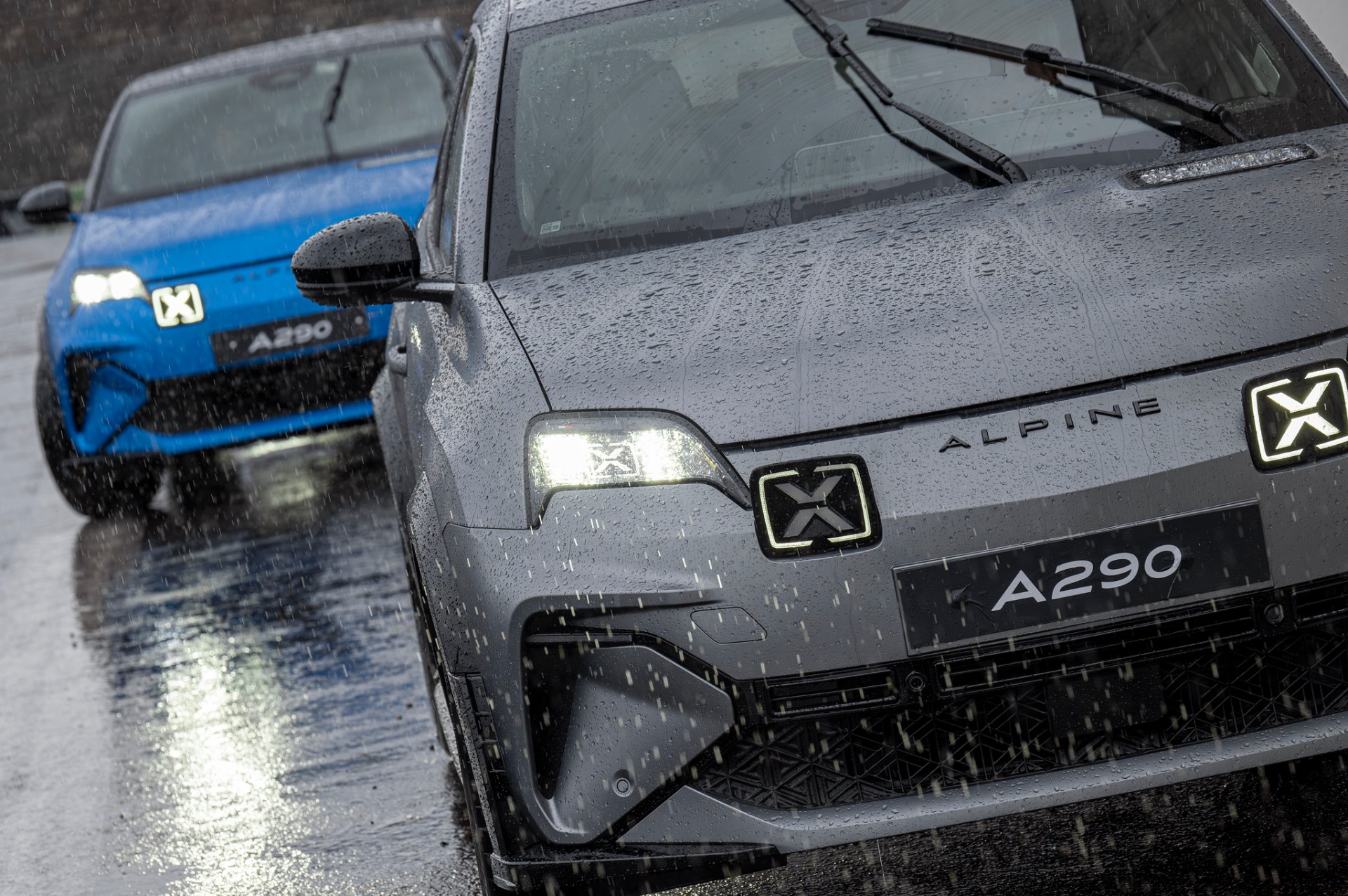 Frentes de dois Alpine A290 — cinzento em primeiro plano e azul atrás — sob chuva