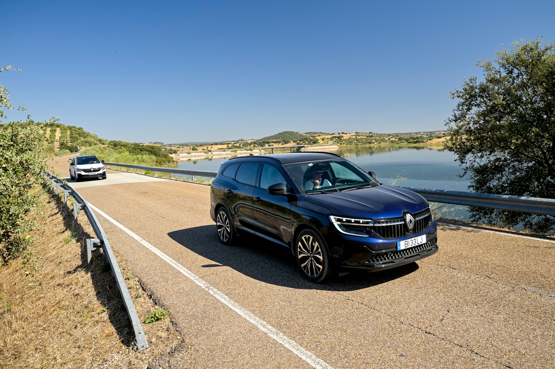 Renault Espace azul em estrada junto a albufeira, com paisagem de Alqueva ao fundo