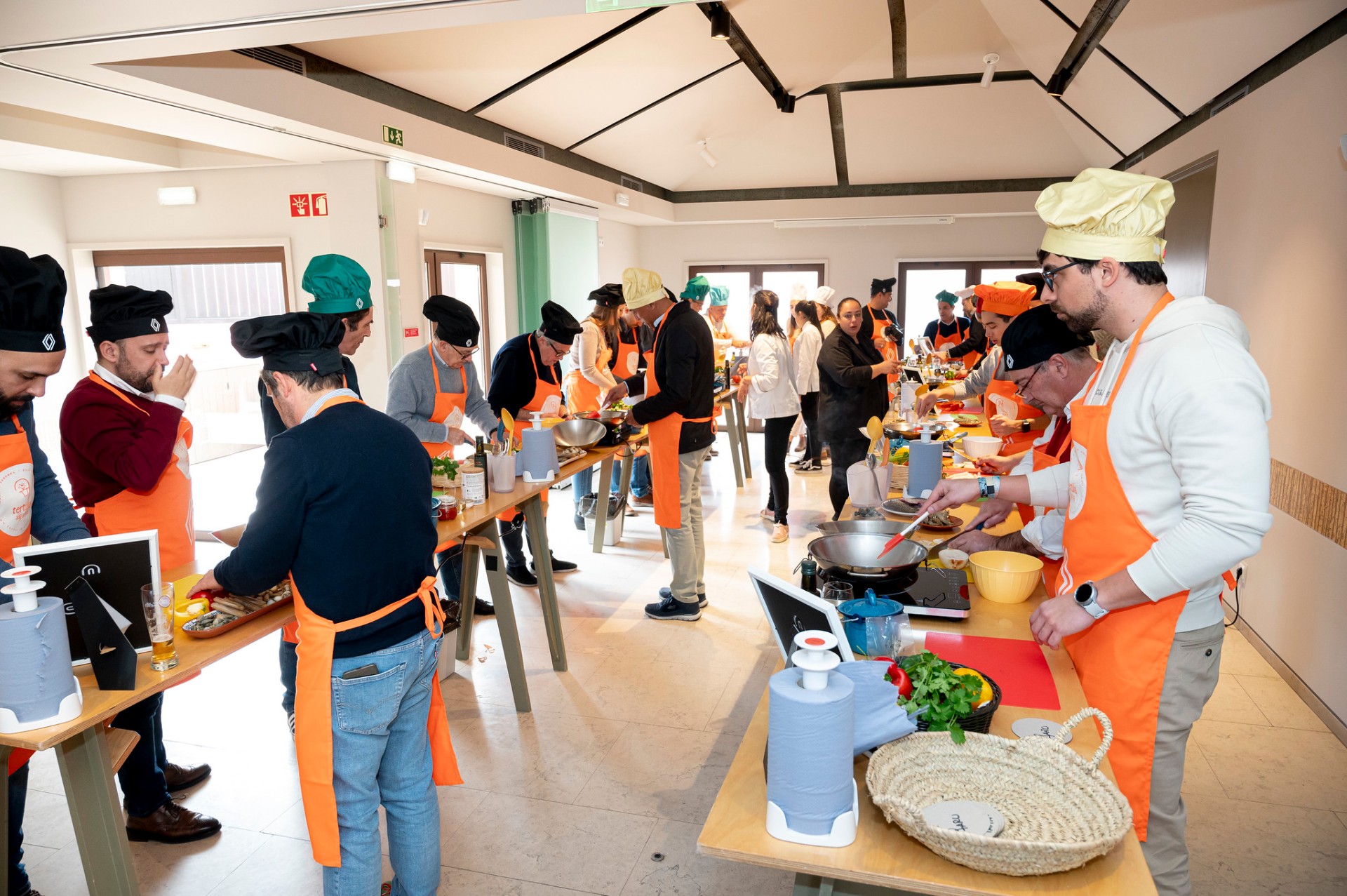 Workshop de cataplana com jornalistas em aventais laranja a cozinhar