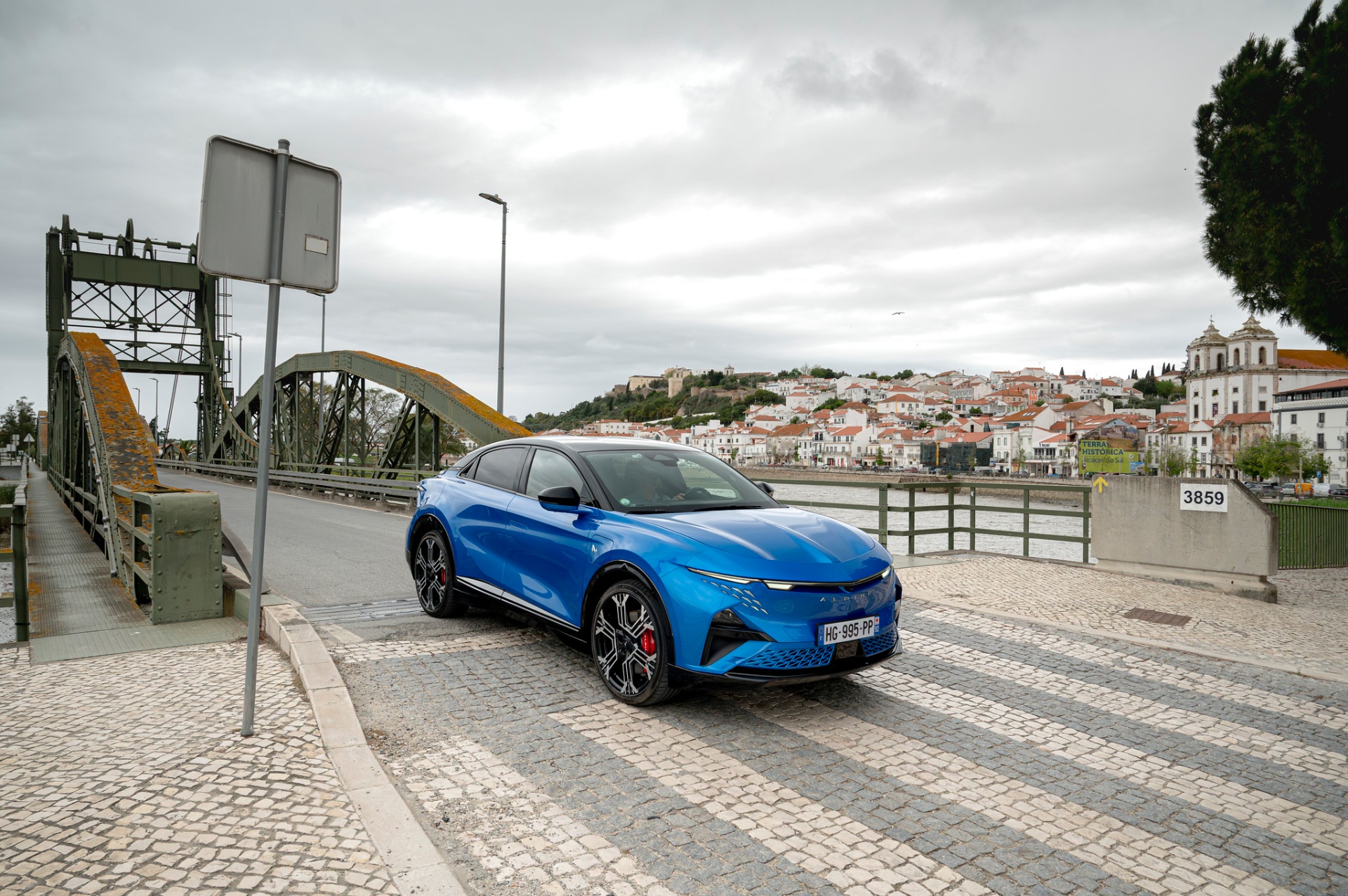 Alpine A390 GT azul junto à ponte metálica e ao casario de Alcácer do Sal