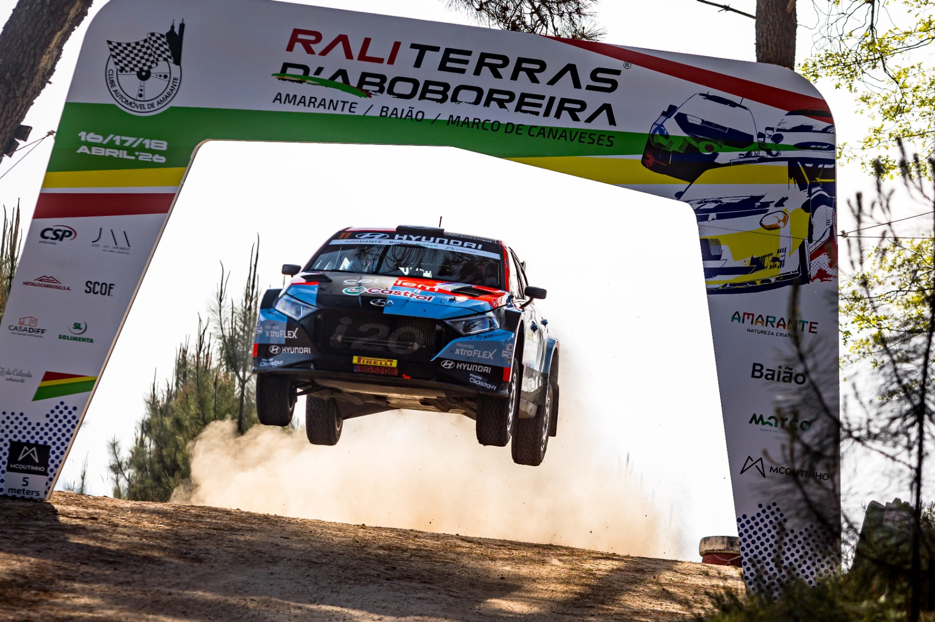 Hyundai i20 do Team Hyundai Portugal em pleno salto sob o pórtico do Rali Terras d'Aboboreira