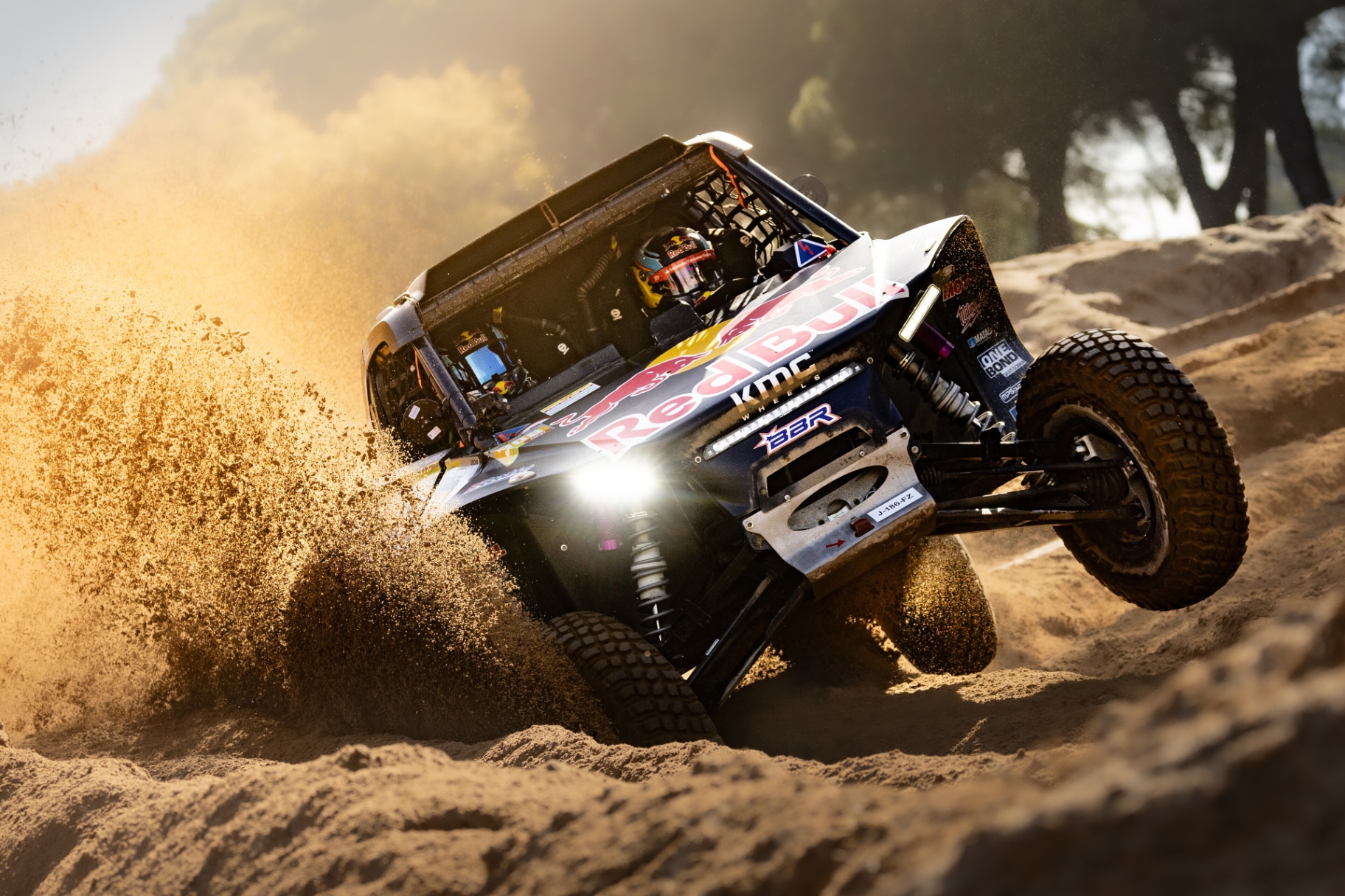 Buggy Red Bull a atacar uma duna de areia levantando jacto de poeira