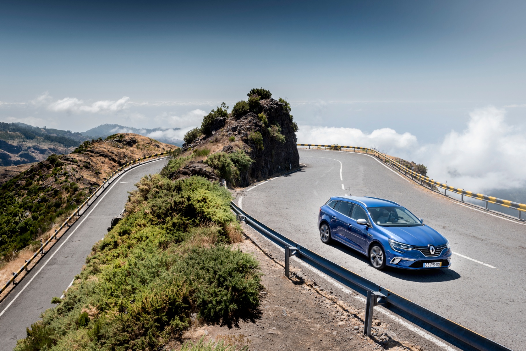Mégane Sport Tourer azul em estrada de montanha acima das nuvens