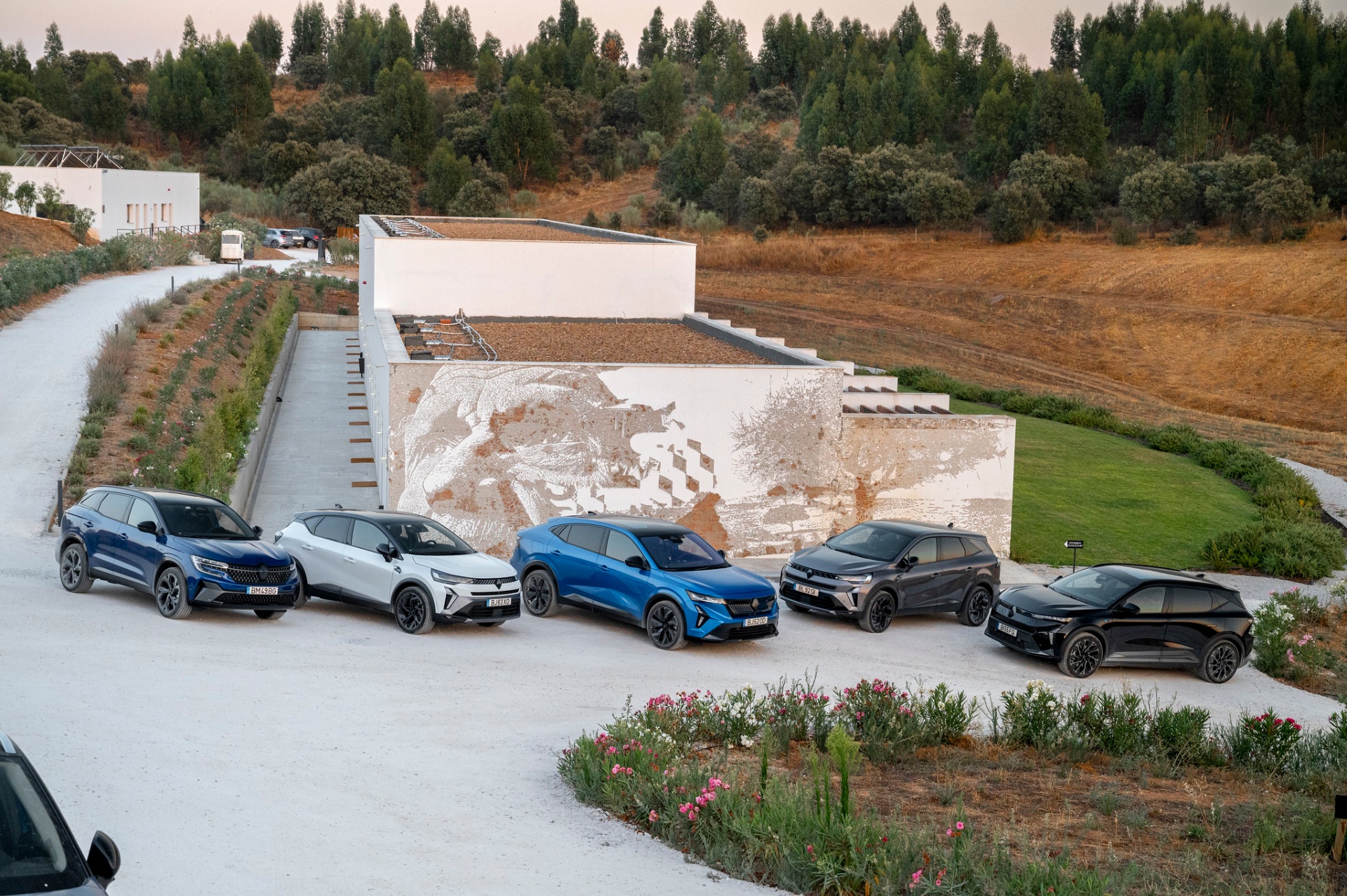 Gama SUV Renault alinhada em frente a mural de arte urbana, ao entardecer no Alentejo