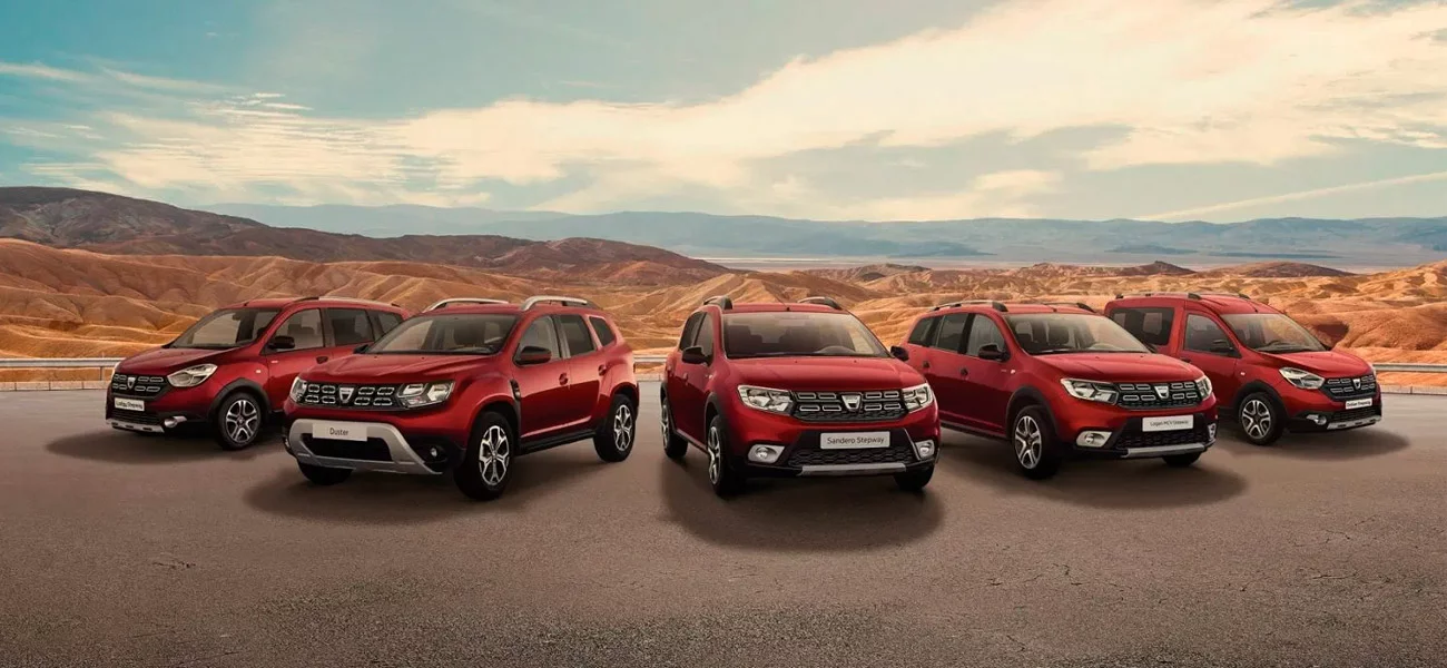 Gama Dacia em vermelho — Lodgy Stepway, Duster, Sandero Stepway, Logan MCV Stepway e Dokker Stepway — alinhada em paisagem desértica de montanhas