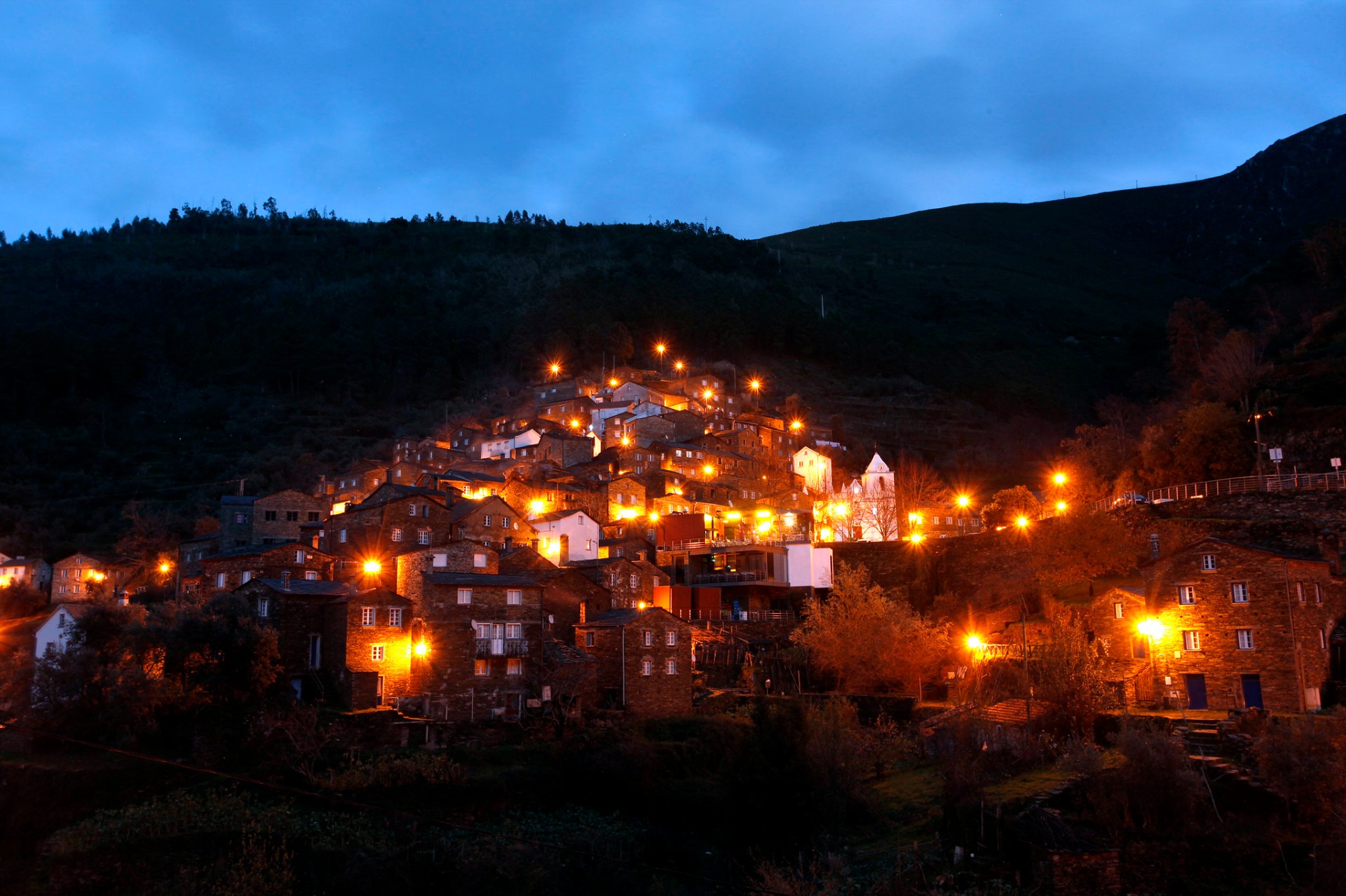 Aldeia do Piódão ao anoitecer, casas de xisto na encosta com candeeiros acesos