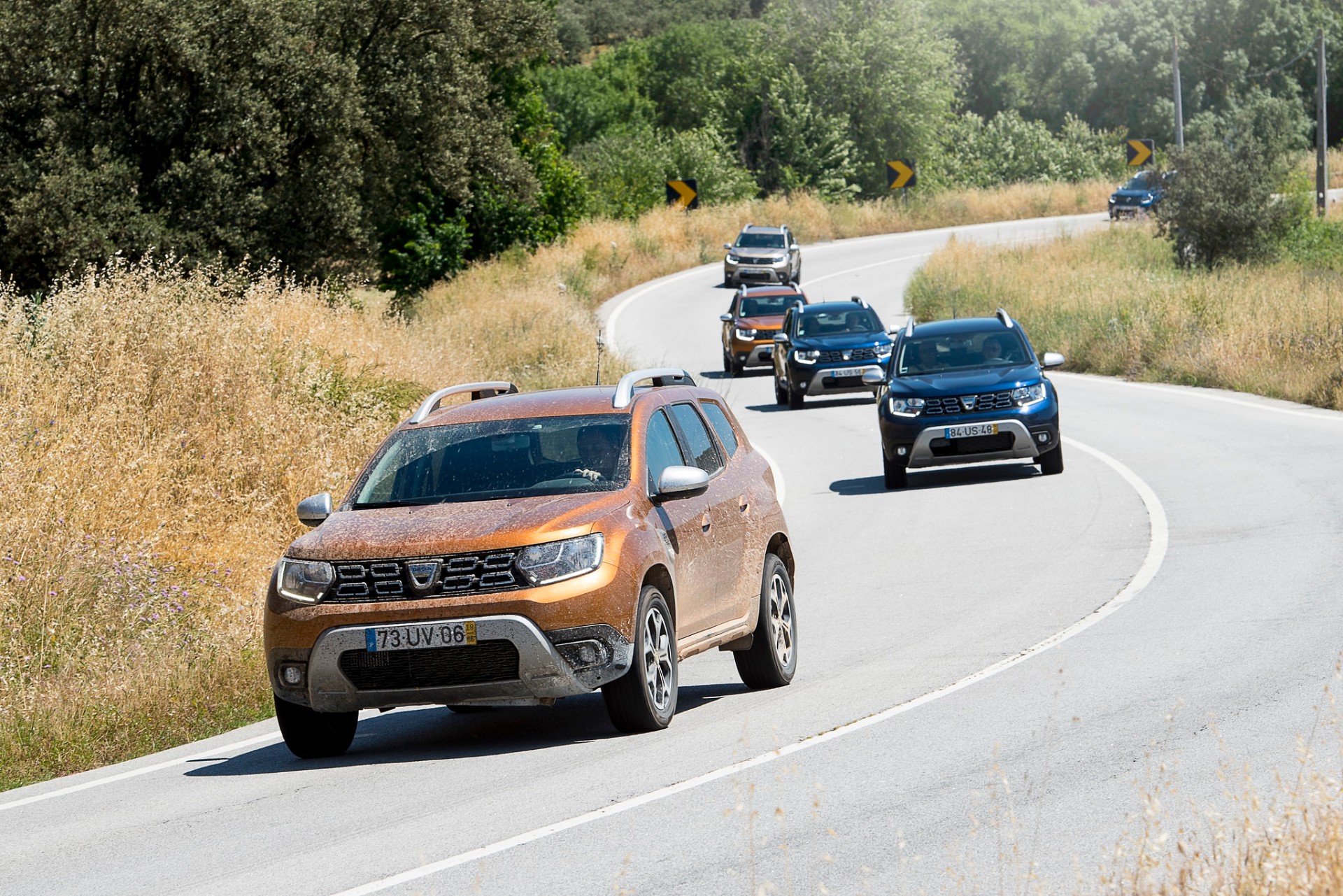 Comboio de Dacia Duster em estrada sinuosa entre vegetação alentejana