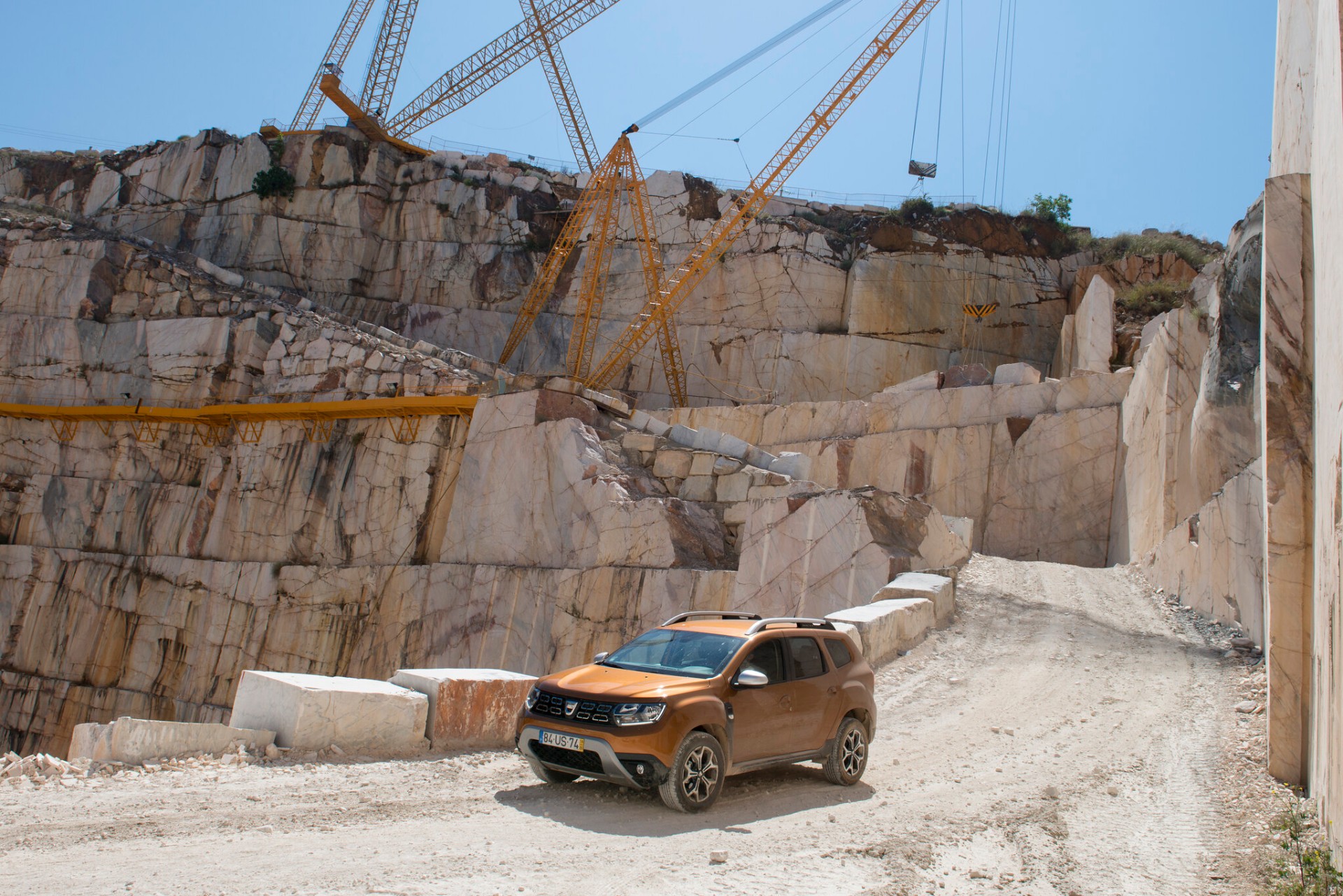 Dacia Duster no fundo da pedreira sob gruas amarelas de extração